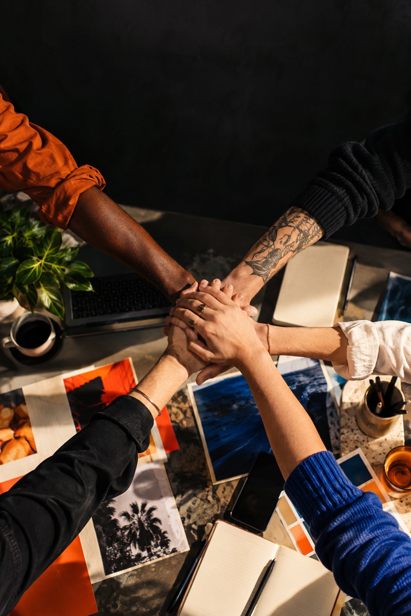 Hands coming together around a creative workspace
